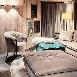 Ein stilvoll eingerichtetes Wohnzimmer mit Fellsessel, High-End Lounge-Sofa und Kunst an der Wand – aufgenommen vom Bluesun Team für Interior Design Fotografie.