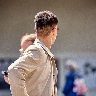 Event photography in Basel – man wearing sunglasses and a trench coat captured from behind at Art Basel by the Bluesun photo team.