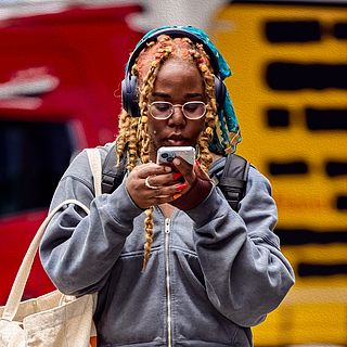 Woman with headphones, smartphone, and canvas bag on her way to Art Basel – an authentic street style moment captured by the Bluesun photo team.