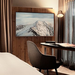 High-quality furnished bedroom with desk, atmospheric lighting and alpine TV picture - photographed by the Bluesun Interior Design Team.