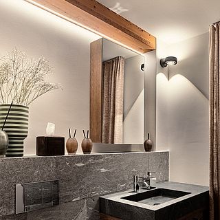 High-quality bathroom with natural stone washbasin, mirror, wooden details and decorative vases - photographed by the Bluesun photo team.