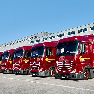 Line of red Galliker Mercedes trucks in front of logistics center, photographed for Galliker Transport AG.