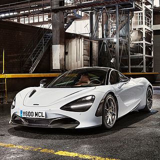 High-end exhibition photography by Bluesun: white McLaren sports car in front of an industrial backdrop – a dynamic composition of technology, light, and form.