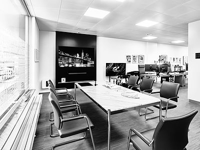 Modern meeting area with a large table, comfortable leather chairs, and screen – part of the open-plan Bluesun studio.