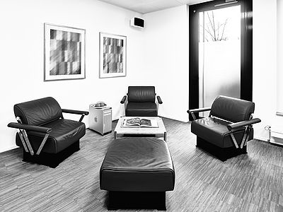Espace lounge du studio Bluesun avec quatre fauteuils en cuir Girsberger confortables, une table basse avec un magazine, une lumière élégante et une ambiance détendue – idéal pour une pause ou une discussion informelle.